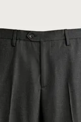 Pantalón de traje slim fit para hombre, color gris oscuro, con bolsillos frontales y bolsillos traseros de doble vivo con botón. Cuenta con cierre frontal de cremallera y botón, y presillas para cinturón.