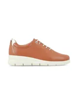 Sneaker de cuero napa color marrón cognac, con cordones blancos, detalle metalizado en el talón y suela elevada blanca.