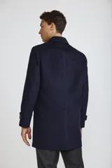 Abrigo tipo carcoat de corte clásico y estructura formal, en color azul marino. Presenta cierre frontal con botones, cuello camisero y bolsillos laterales. El interior cuenta con un forro oscuro con detalles en contraste.