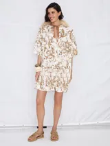 Vestido corto con estampado de arabescos color beige y marrón, escote en V y mangas cortas.