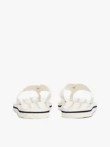 Ojotas blancas con tiras de tejido trenzado y una pequeña insignia con el monograma TH a contraste en la tira del dedo. La suela es de EVA con una línea decorativa azul marino en el borde.