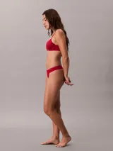 Bombacha tipo colaless Calvin Klein de la línea Ideal Cotton, confeccionada en mezcla de algodón elástico. Presenta un diseño minimalista con cintura fina y flexible, y cuenta con el logo de la marca estampado en el lateral.