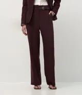 Pantalón de sastrería corte recto, color bordó con estampado de rayas finas verticales. Confeccionado en crepé, cuenta con cintura estructurada con trabillas, bolsillos funcionales y un medio cinturón incorporado de material sintético con hebilla metálica.