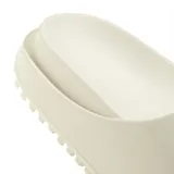 Ojotas de diseño deslizante color beige, con tira ancha en el empeine que presenta el logotipo del trifolio de Adidas en relieve.