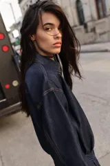Camisa amplia de denim azul oscuro con cuello solapa, manga larga, bolsillo de plastrón en el pecho y cierre frontal con botones a presión dorados.