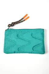 Billetera tipo sobre color turquesa con diseño acolchado de costuras en zigzag. Cuenta con cierre superior y un tirador de cordón trenzado multicolor con punteras naranjas.