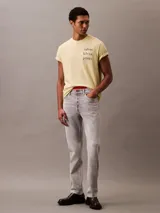 Remera color crema de algodón con cuello redondo y mangas cortas con dobladillo. Estampado vertical con el logo de Calvin Klein Jeans en el frente.