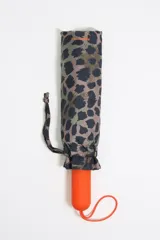 Paraguas plegable de tejido técnico con estampado animal print en tonos verdes y negros. Presenta un mango de color naranja con el logo de la marca grabado y una funda protectora con el mismo diseño.