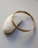 Esclava rígida de diseño artesanal con textura irregular y acabado metálico, ideal para uso diario.