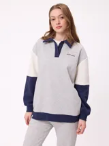 Sweater estilo rugby de Rusty, con diseño color block en tonos bordó, azul marino y verde. Presenta cuello polo en color crema con cierre frontal de botones, mangas largas con puños elásticos y logo de la marca bordado en el pecho.