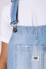 Jardinero de jean en color celeste claro con lavado desgastado. Presenta un diseño clásico con bolsillo frontal en el pecho, breteles regulables con hebillas metálicas y corte relaxed de pierna recta.