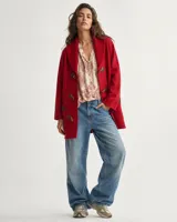 Sacón de lana merino color rojo, con cuello chal tejido en rib, bolsillos frontales y cierre con botones tipo duffle de presillas de cuero y madera.
