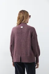 Polera gris de tejido suave de punto, con cuello alto, mangas abullonadas, puños elásticos y diseño relajado.