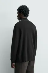 Chaqueta regular fit de punto tejido en hilatura de algodón, color negro, con cuello subido y manga larga, acabados en rib y cierre frontal con cremallera.