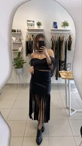 Falda midi negra de gabardina metalizada elastizada, con tachas en la cintura y flecos en el ruedo.