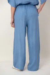 Pantalón palazzo de lino color blanco, con cintura elástica fruncida, bolsillos laterales y detalle de alforzas verticales en los laterales.