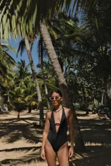 Traje de baño enterizo negro con escote halter profundo y argolla decorativa en el centro.