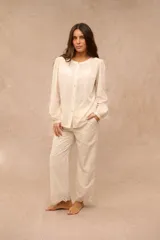 Camisa de algodón color crudo, con mangas largas abullonadas y puños elásticos. Presenta diseño con bordados tipo broderie en toda la prenda y cierre frontal con botones.