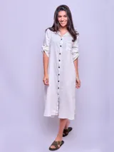 Vestido camisero largo color verde militar, confeccionado en lino, con cuello clásico, mangas largas con puños abotonados y cierre frontal con botones. Incluye un bolsillo de parche en el pecho.