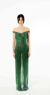 Vestido largo color verde esmeralda con escote off-shoulder y busto drapeado. La falda está compuesta por flecos bordados que crean movimiento.