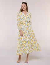 Vestido maxi de gasa con estampado floral en tonos amarillos y verdes sobre base blanca, escote en V cruzado, mangas largas y cintura elastizada con lazo.