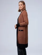 Cardigan largo tejido color marrón con ribetes negros en contraste, bolsillos delanteros y mangas largas.