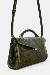 Bolso de mano de formato alargado con textura de efecto cocodrilo. Cuenta con asa de mano superior, asa extraíble para usar como bandolera, bolsillo interior con cierre y cierre frontal mediante clip metálico.