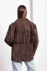 Campera marrón de gamuza con corte masculino, hombros marcados y caída recta. Tiene flecos largos en la espalda y mangas.