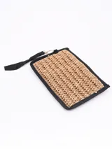 Monedero tipo sobre de paja trenzada color arena, con borde y correa de mano marrón.