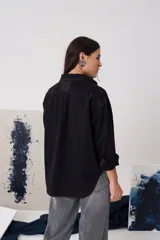 Camisa de gabardina con cuello clásico, cierre frontal de botones y mangas largas con puños vueltos. Presenta un diseño de corte recto y acabado desgastado.