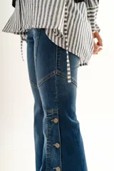 Jean estilo oxford de tiro medio, color negro, con recortes curvos en las piernas y botones decorativos en la botamanga.