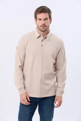 Remera polo de manga larga confeccionada en jersey, con cuello clásico y cierre frontal de tres botones. Presenta puños acanalados y un diseño liso en color beige.