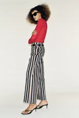 Pantalón de tiro alto y pernera recta con estampado de rayas verticales en tonos azul, marrón y beige. Incluye un cinturón delgado de color marrón oscuro con hebilla metálica dorada.