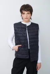 Chaleco acolchado tipo puffer color negro, con cierre frontal de botones a presión, cuello redondo y bolsillos laterales.