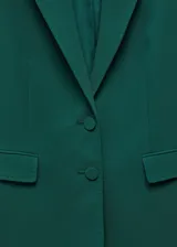 Blazer verde esmeralda de corte recto, con solapas de muesca, cierre frontal de dos botones, dos bolsillos delanteros con solapa y forro interior.