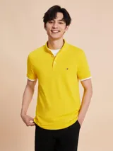 Chomba amarilla de corte slim, con cuello clásico, cartera de dos botones y logo de Tommy Hilfiger bordado en el pecho.