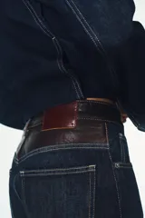 Jeans de tiro alto y pierna ancha con diseño de cinco bolsillos. Presenta una aplicación en la cintura de piel a contraste y cierre frontal con cremallera y botón metálico.