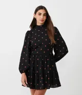 Vestido corto negro de chiffon con estampado de pequeños corazones naranjas, cuello alto, mangas largas abullonadas y falda con volados en capas.