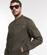 Chaqueta bomber azul marino lisa, con cierre frontal, cuello redondo y bolsillos laterales.