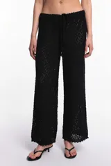 Pantalón blanco de tejido calado con diseño de rombos, cintura elástica con cordón ajustable y ruedo con terminación ondulada.