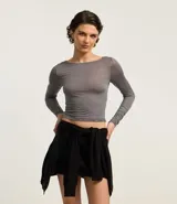 Blusa de manga larga confeccionada en tejido rib con textura acanalada y leve transparencia. Presenta un corte ajustado al cuerpo y escote redondo.