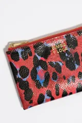 Monedero de tamaño grande con estructura rígida y exterior con textura brillante, estampado animal print en tonos rojo, negro y azul. Cuenta con cierre de cremallera dorado, logo metálico de Bimba y Lola y tarjetero interior.