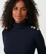 Blusa de punto acanalado en color azul marino, con cuello alto y detalle de botones dorados decorativos en los hombros. Presenta un diseño ajustado de manga larga.