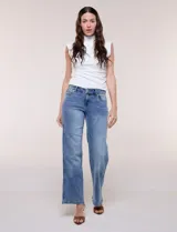 Jean wide leg de tiro medio, color azul con efecto lavado, corte amplio y diseño de cinco bolsillos. Presenta cintura con presillas y pretina con broches metálicos para regular el ajuste.