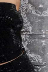 Top strapless confeccionado en tejido elástico con apliques de strass que aportan un efecto brillante tipo glitter. Silueta al cuerpo, calce cómodo y sin cierre.