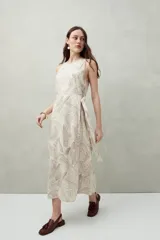 Vestido largo sin mangas color beige con estampado sutil, lazo lateral, cruce y abertura frontal.
