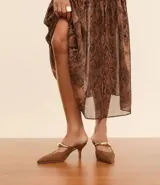 Zapato de tacón marrón con puntera fina y tira ancha dorada.