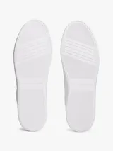 Zapatillas de tenis minimalistas Tommy Hilfiger, confeccionadas en piel napa blanca con suela gruesa tipo cupsole. Presentan un diseño de corte bajo con cordones, detalle de panel azul marino en el talón y logo metálico de la marca en el lateral.