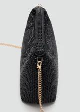 Bolso de mano estructurado color negro con acabado de brillos o strass, asa corta y cierre superior con cremallera.