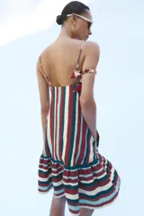 Vestido mini confeccionado en hilatura con lino, de escote recto con tirantes finos ajustables y bajo acabado con volantes, con diseño de rayas verticales en la parte superior y horizontales en el volante.